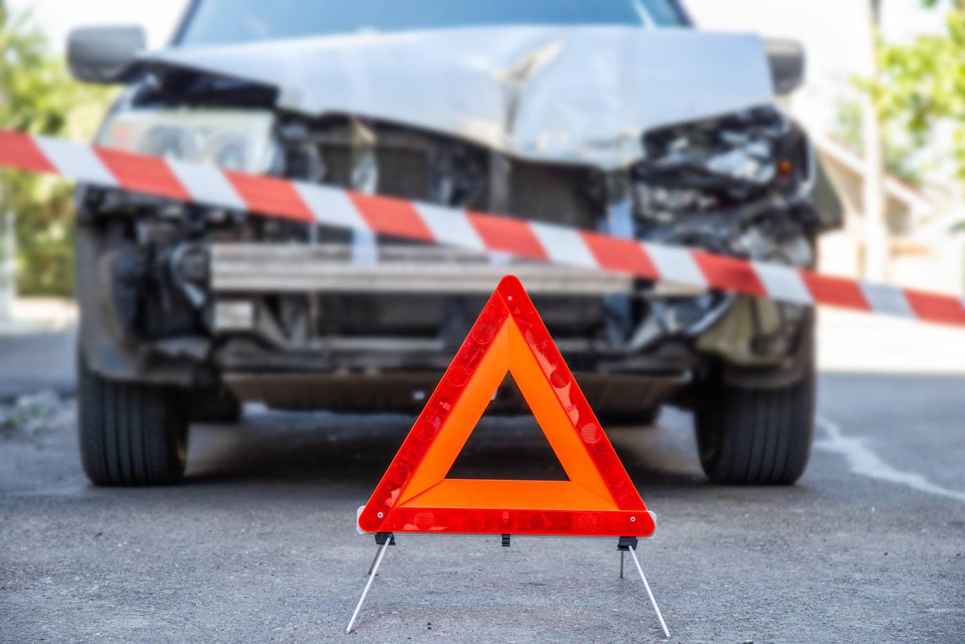Triangle de signalisation et rubalise devant un véhicule accidenté